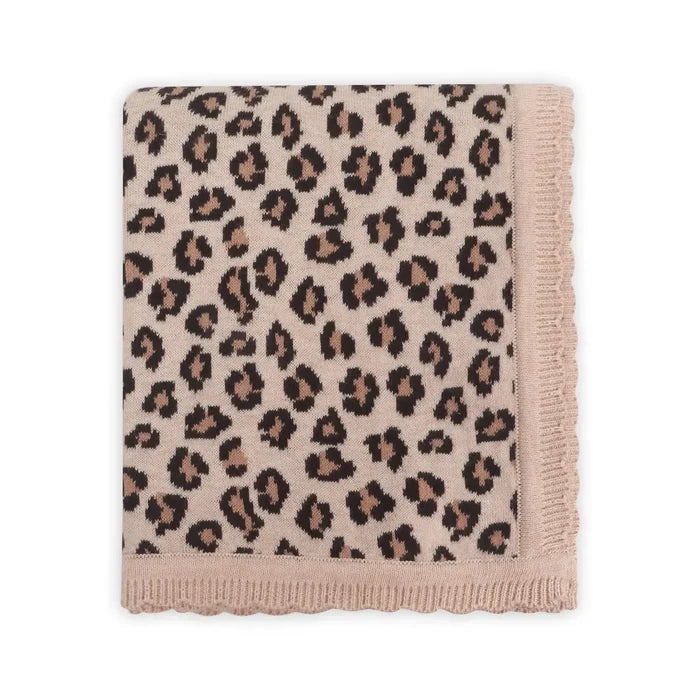 A folded knit blanket featuring a leopard print pattern in beige, brown, and black, finished with a soft dusty pink scalloped border.