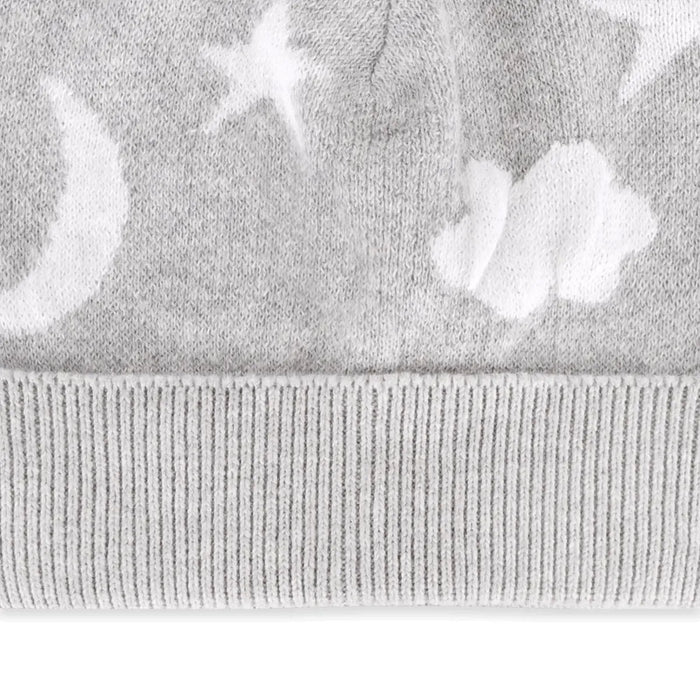 Close-up of a light gray knit fabric with a white moon, star, and cloud pattern, featuring a ribbed cuff.