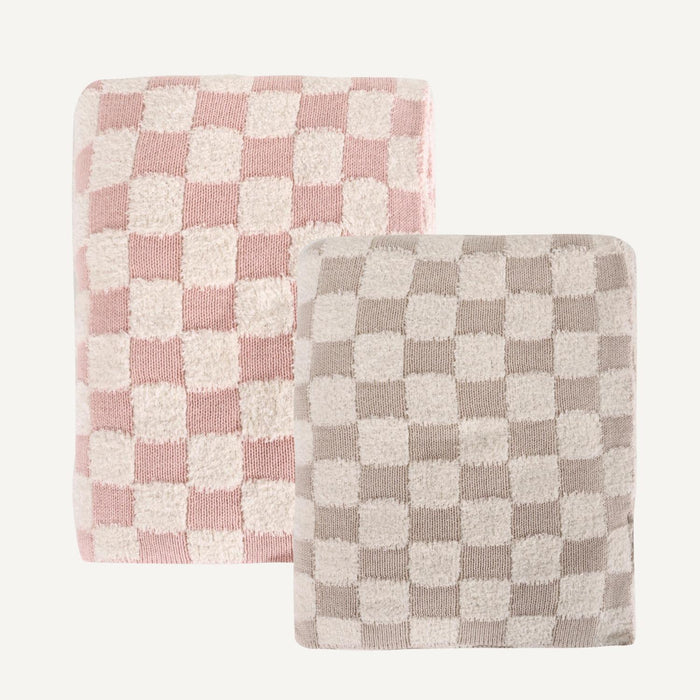Two folded plush towels with checkerboard patterns, one in dusty pink and cream, and the other in taupe and cream, displayed on a clean off-white background.