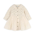 A cream-colored baby dress with a textured knit bodice, long sleeves, and a gathered flared skirt, featuring a button-up front.