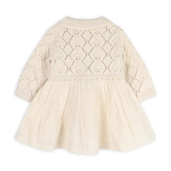 An off-white baby dress with a long-sleeve knit cardigan-style back and a gathered tulle skirt, shown from the back on a white background.