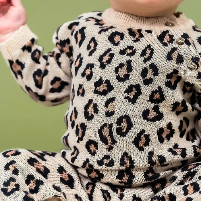 Child wearing a leopard print outfit against a green background