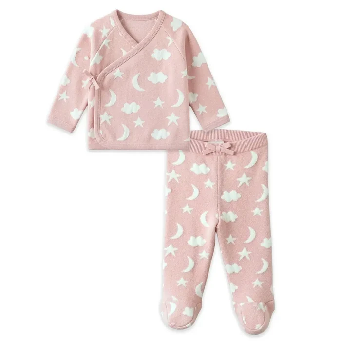 A baby sleepwear set consisting of a pink long-sleeve wrap top and matching footed pants, both printed with a white pattern of stars, moons, and clouds, displayed on a clean white background.