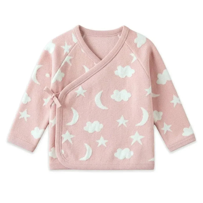 A pink long-sleeve baby wrap jacket with a white celestial pattern of stars, moons, and clouds, featuring a side tie closure, shown on a plain white background.