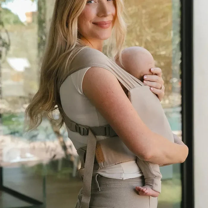 Woman holding a baby in a carrier outdoors