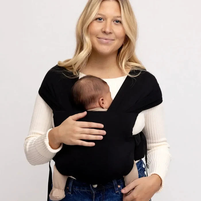 Woman holding carrying baby in a black wrap on a white background