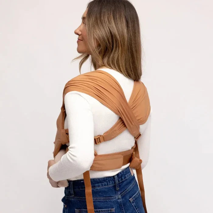 Person wearing a brown baby carrier against a white background