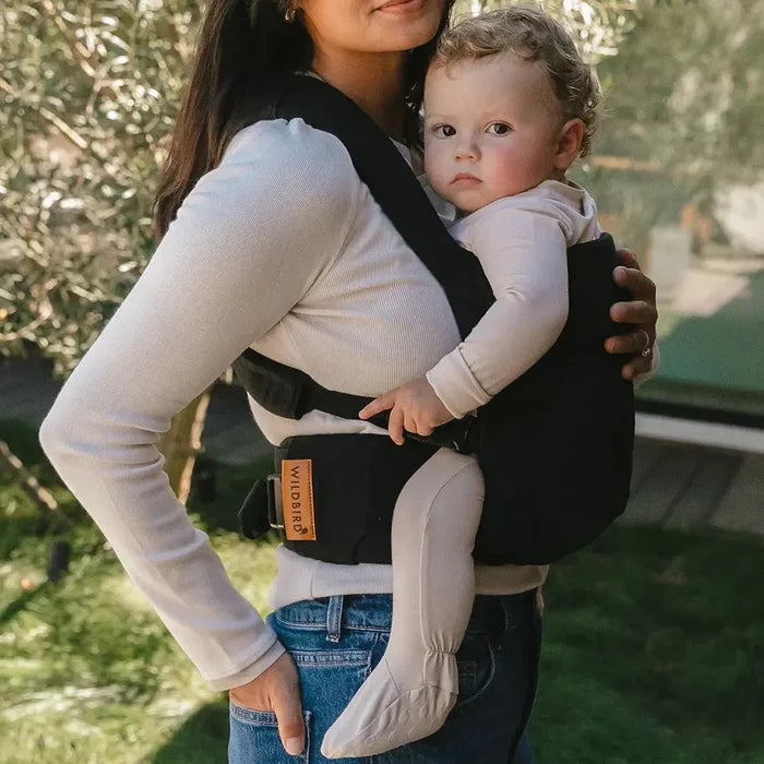 Woman holding a baby in a carrier outdoors