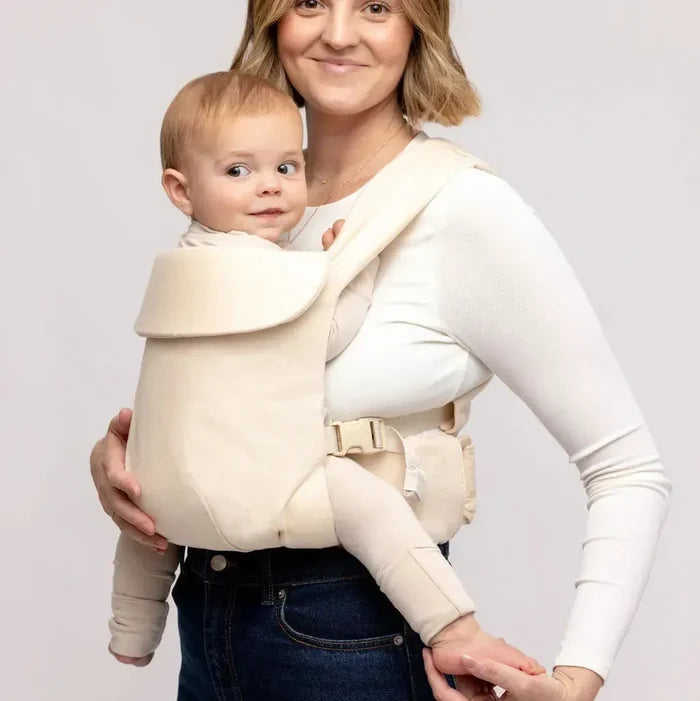 Woman carrying baby in a cream colored baby carrier on a white background